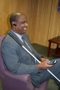 Blind person using iPhone with Bluetooth earpiece while using NFB-NEWSLINE app