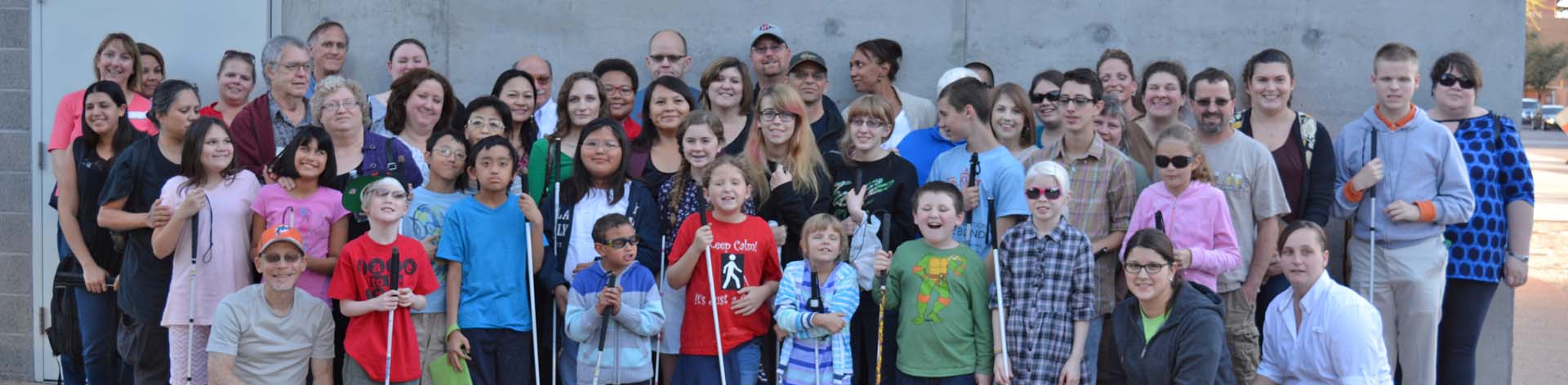 A ;arge group of blind students and mentors pose together after a successful NFB EQ outing.